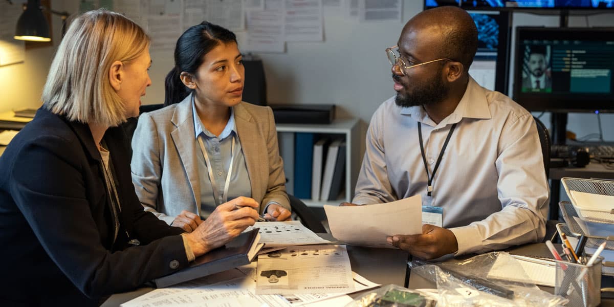 Two women and a man sitting down looking over paperwork