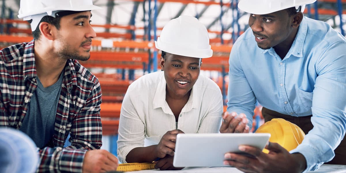 two men and a woman over looking plans at a real estate project